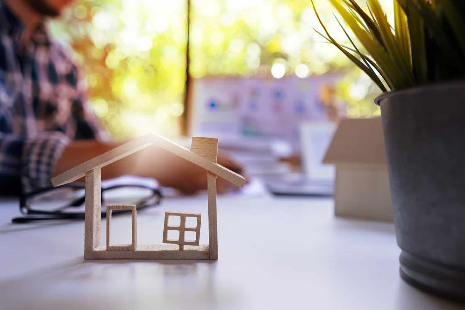 房地产估价职业概念。评估师以房屋模型为前景计算房屋价值的工作背景。