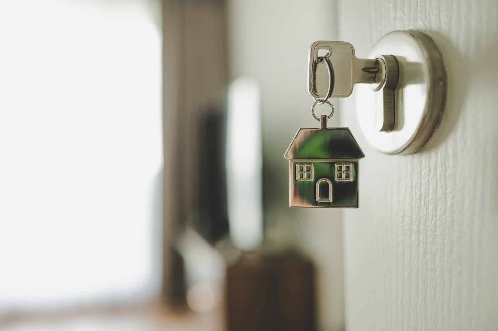 打开门和门把手使用密钥和密钥链形状的房子。房地产投资和房屋抵押贷款金融地产的概念